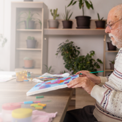 Elderly man painting at a memory care facility, engaging in a dementia-friendly activity.